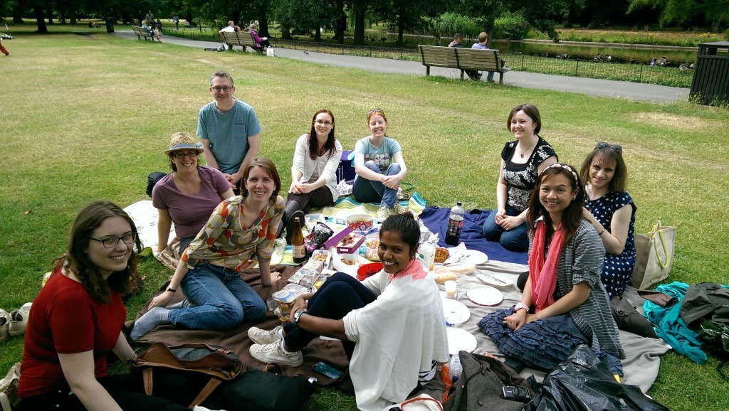 10 people sitting on picnic blankets in Regent's Park. All are smiling at the camera.